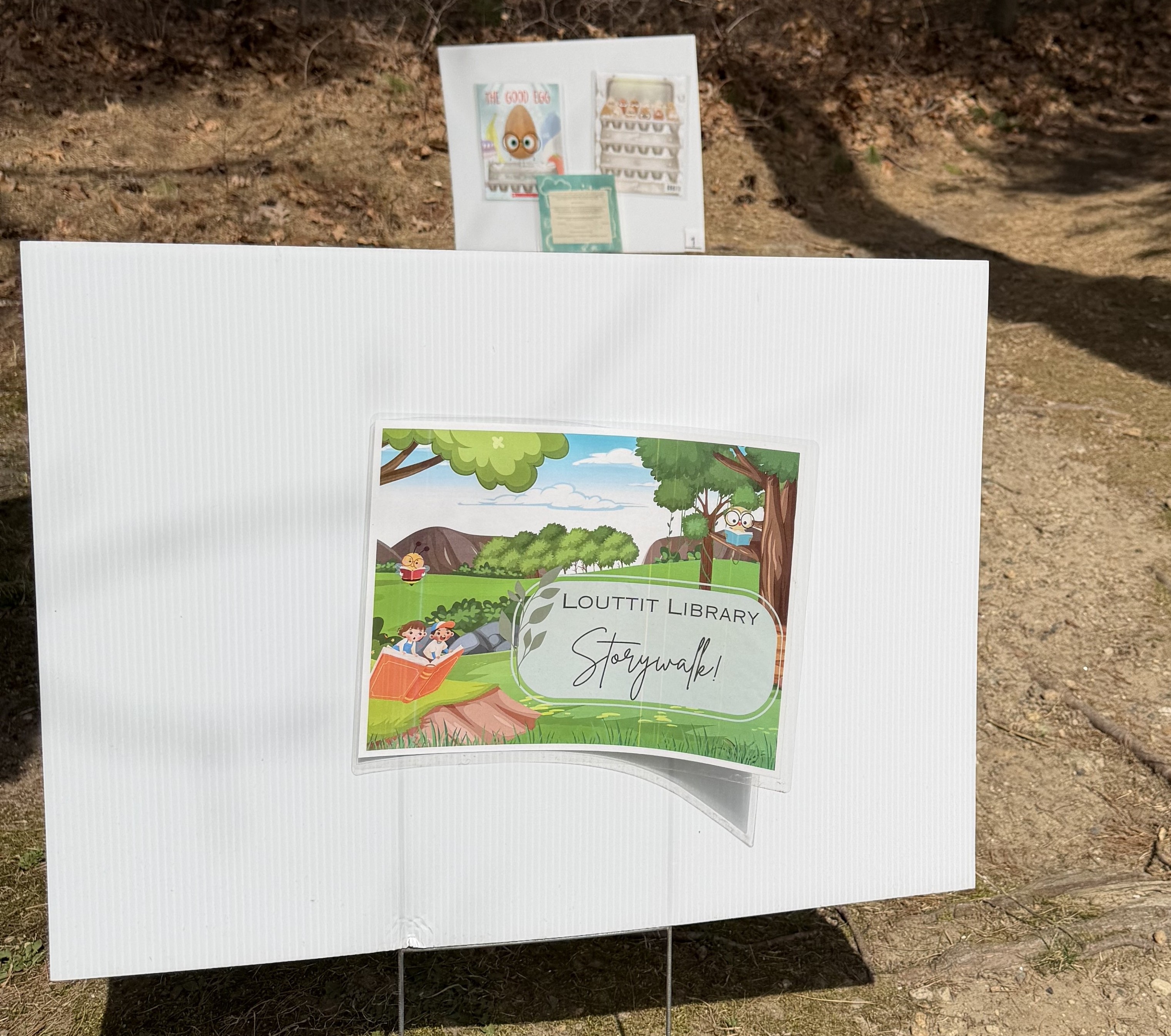 Storywalk sign on a white background on the trail.